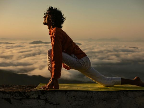 Silhouette of a person in a warrior yoga pose during sunrise.
